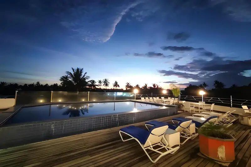 Terrasse avec piscine et transats au coucher du soleil.