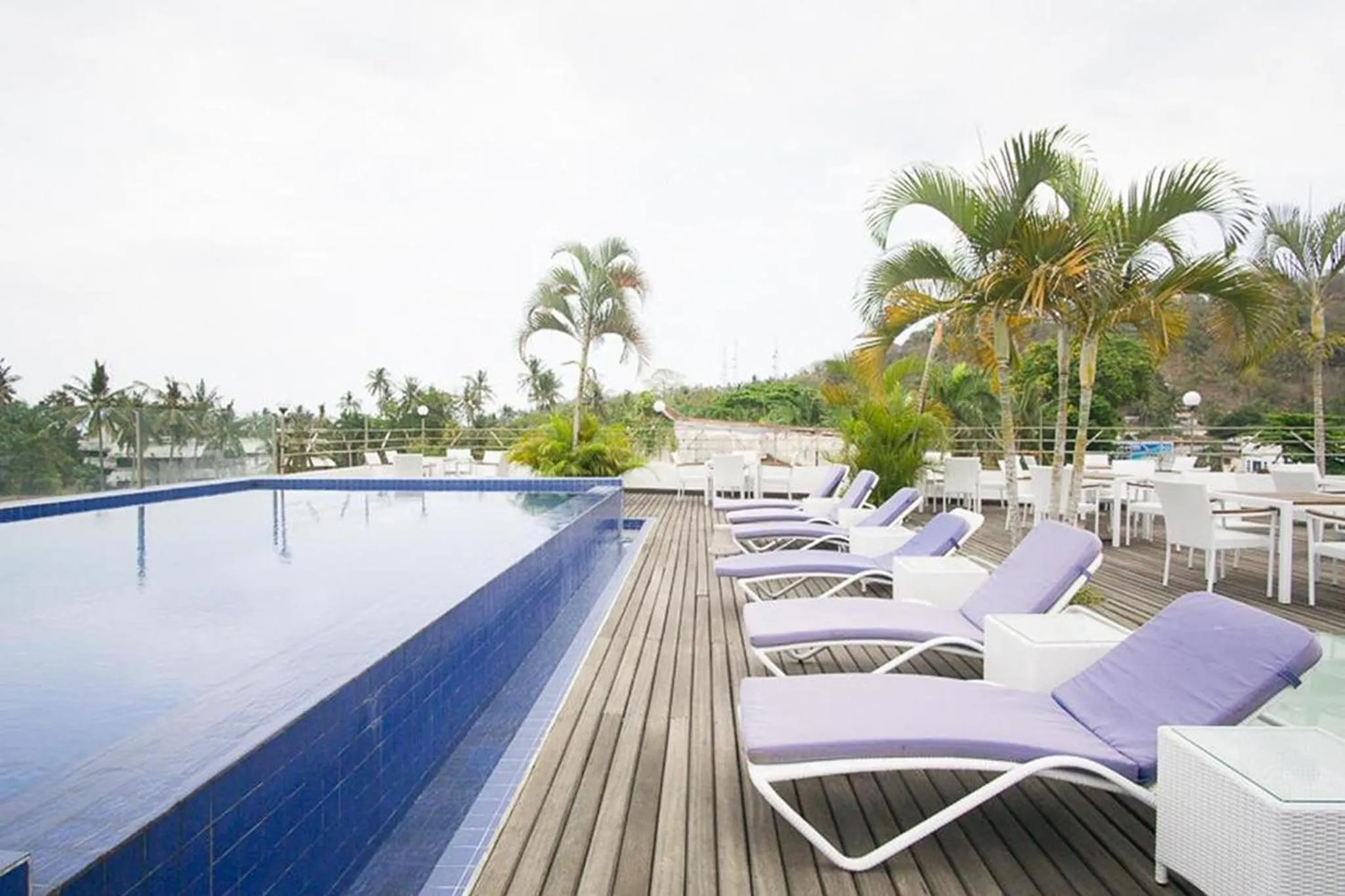 Terrasse avec transats et piscine à débordement donnant sur la mer.
