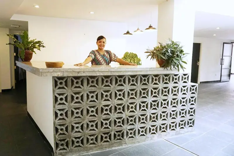 Une employée se tient derrière un comptoir d'accueil dans un hall lumineux.