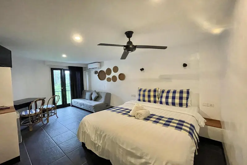 Une chambre lumineuse avec un lit fait et un coin salon.