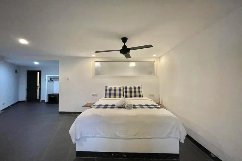 Une chambre lumineuse avec un grand lit recouvert d'une courtepointe bleue et blanche.