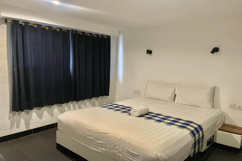 Une chambre lumineuse avec un grand lit recouvert d'une couverture bleue et blanche.