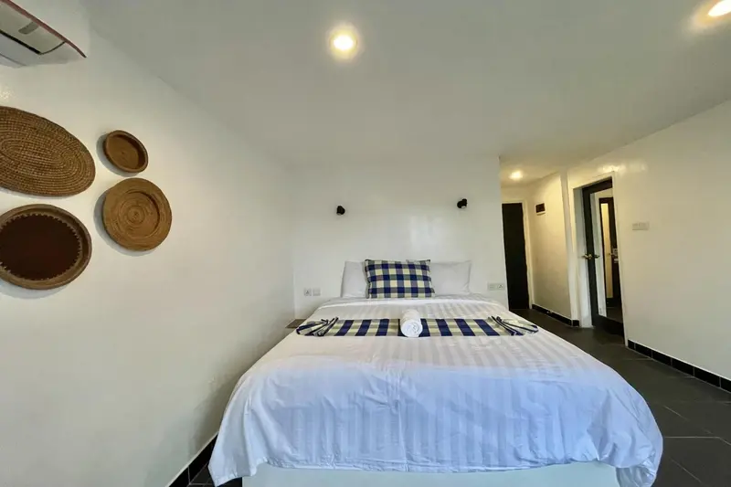 Une chambre lumineuse avec un grand lit recouvert d'une courtepointe à carreaux.