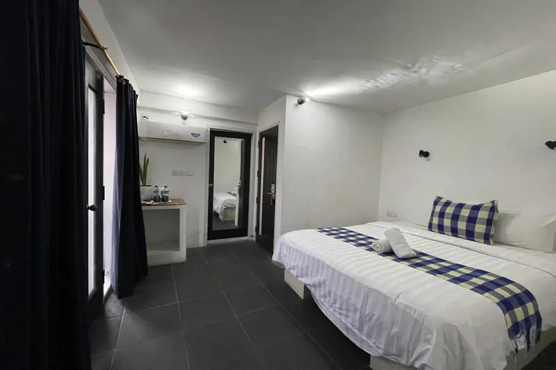 Une chambre lumineuse avec un lit recouvert d'une courtepointe bleue et blanche.