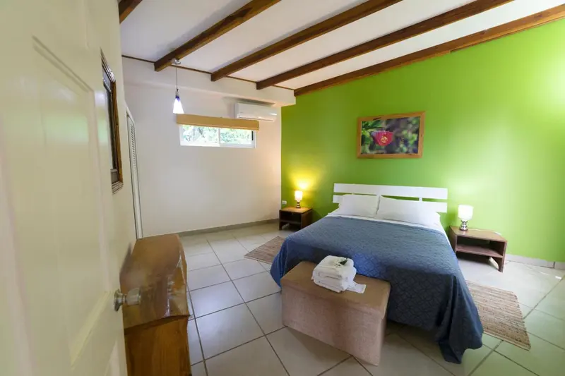 Chambre lumineuse avec un lit recouvert d'une courtepointe bleue et des meubles en bois.