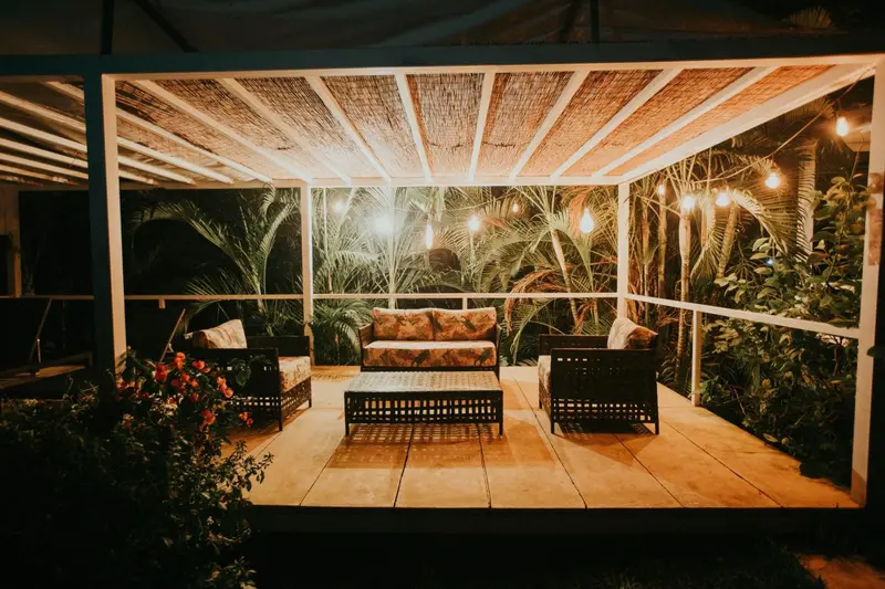 Espace de détente extérieur avec mobilier en rotin et éclairage festif.