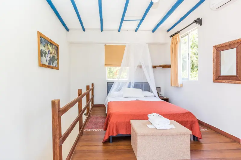 Une chambre lumineuse avec un lit recouvert d'une moustiquaire et un décor mural.