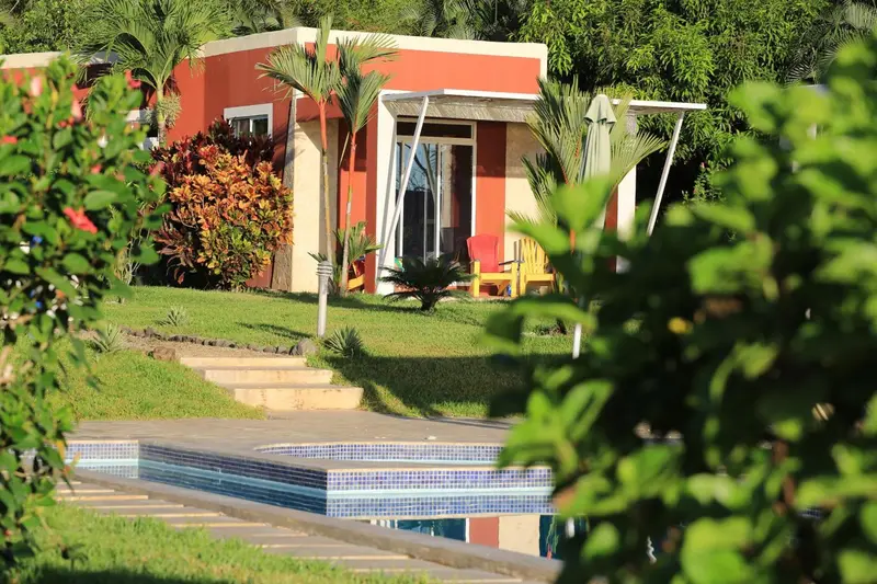 Petites maisons colorées avec terrasse et piscine en bord de pelouse.