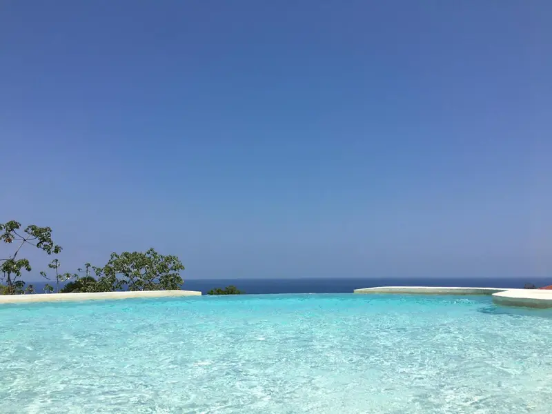 Piscine à débordement avec vue sur l'océan et le ciel bleu.