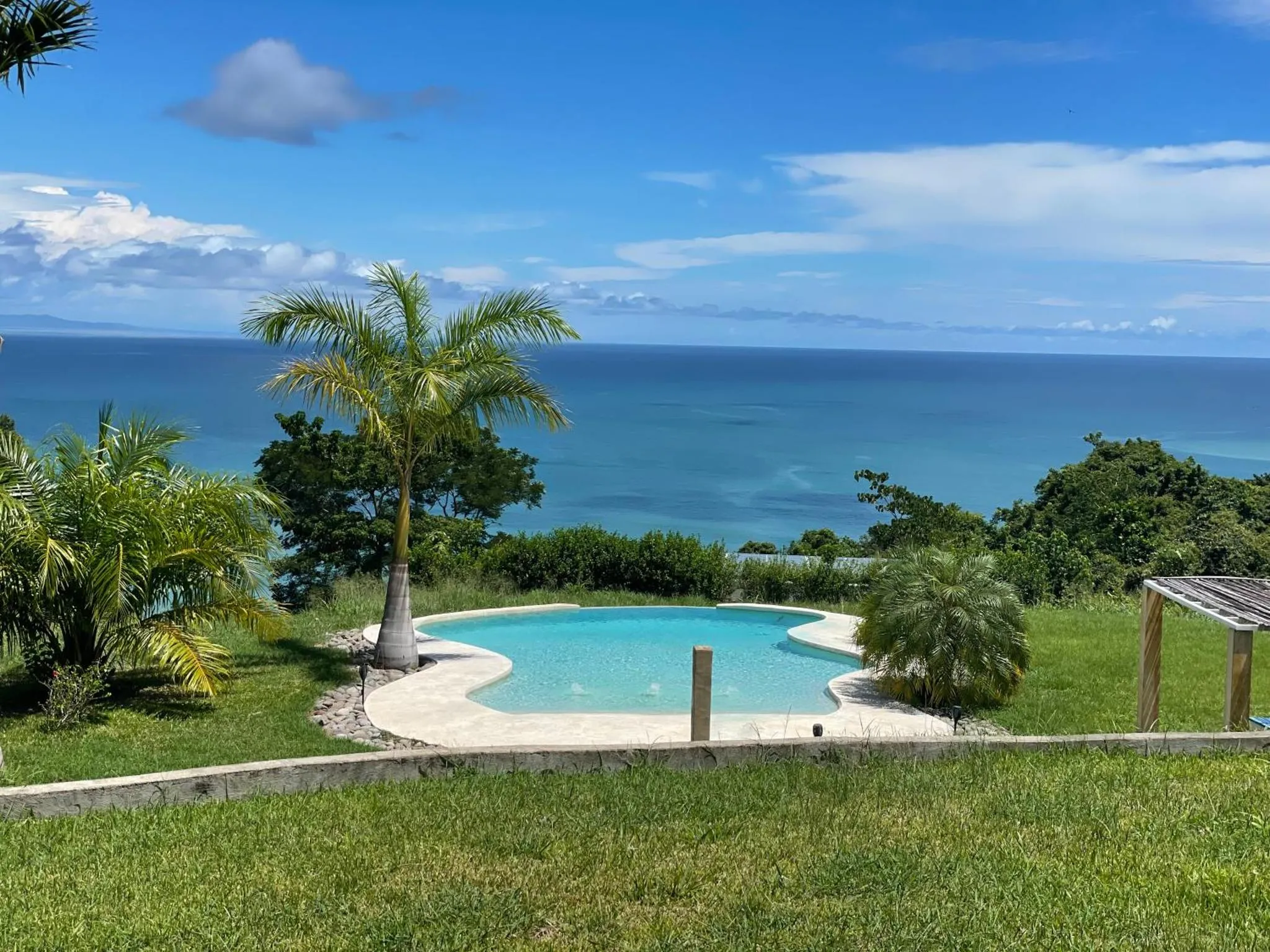 Petite piscine en bordure d'une pelouse verdoyante avec vue sur la mer.