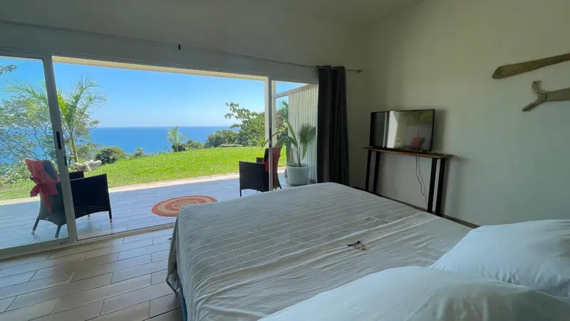 Une chambre lumineuse s'ouvre sur une terrasse avec vue sur la mer.