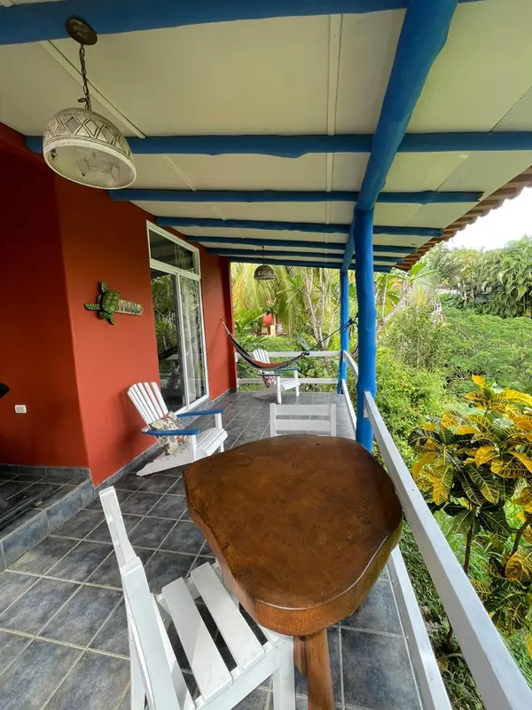 Terrasse ombragée avec mobilier en bois et vue sur la végétation.