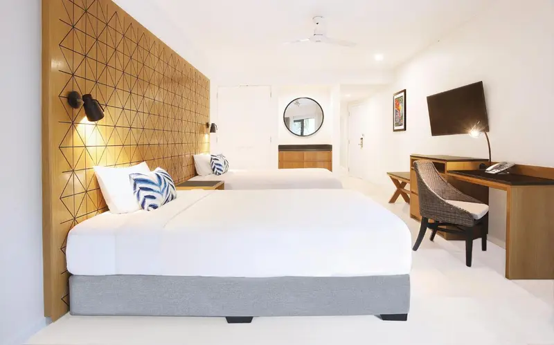 Une chambre lumineuse avec deux lits simples et un bureau.