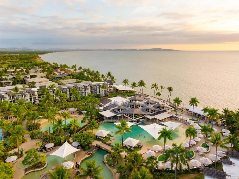 Vue aérienne d'un complexe hôtelier tropical au bord de la mer au coucher du soleil.