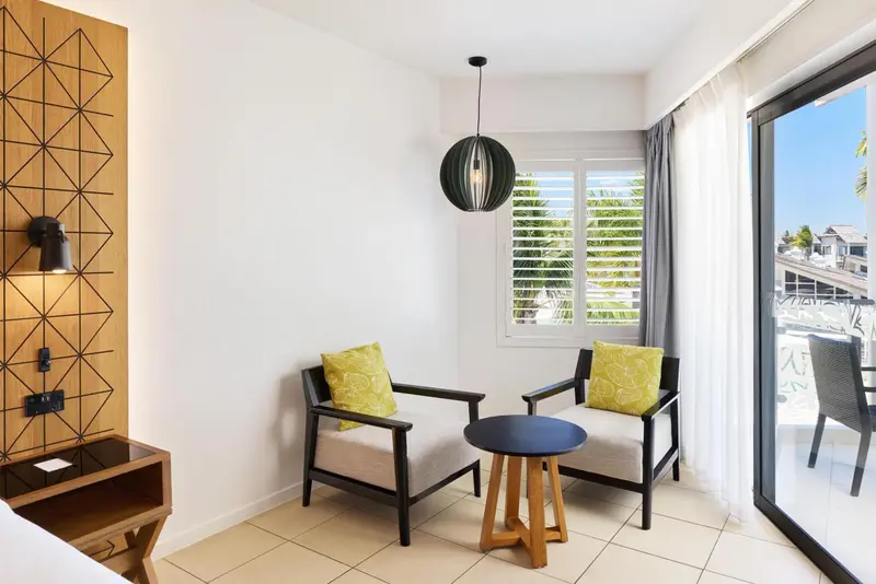 Un coin salon lumineux avec deux fauteuils verts et une table basse.