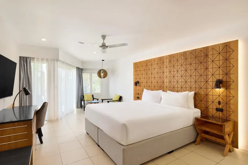 Une chambre lumineuse avec un grand lit et un décor mural en bois.