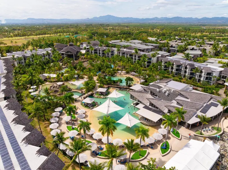 Vue aérienne d'un complexe hôtelier avec piscine et végétation luxuriante.