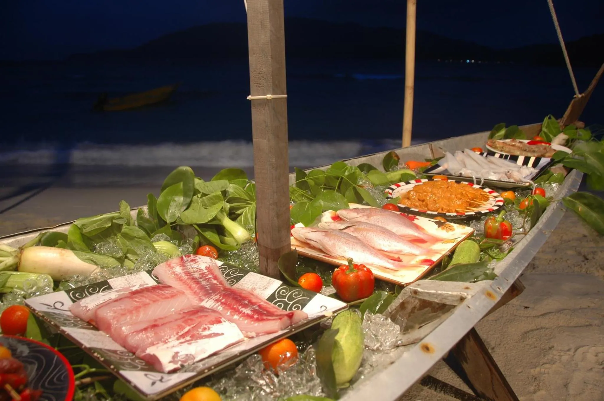 Présentation de poissons frais et de légumes sur un buffet en bord de mer.