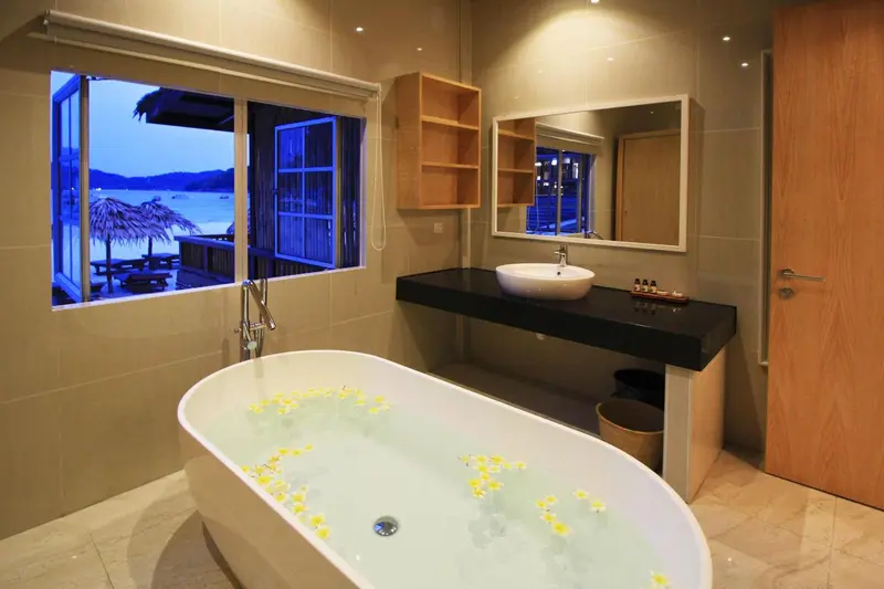 Une baignoire remplie d'eau est visible dans une salle de bain lumineuse avec vue sur la mer.