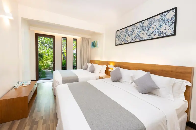 Chambre lumineuse avec deux lits simples et une décoration sobre.
