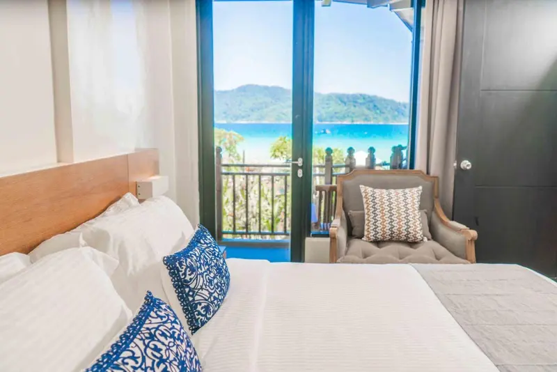 Une chambre lumineuse avec un lit fait et une vue sur la mer.