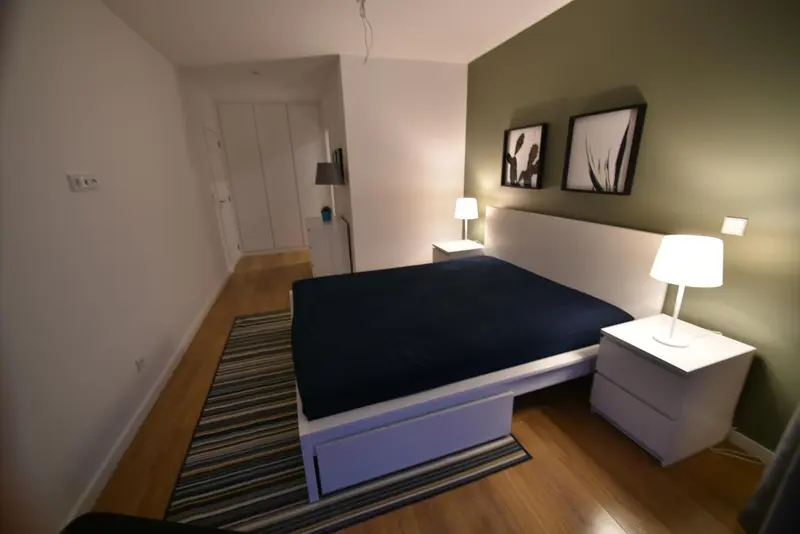 Une chambre avec un grand lit recouvert d'une couverture sombre et des lampes de chevet.