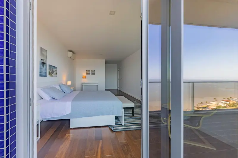 Chambre lumineuse avec un grand lit et vue sur la mer.