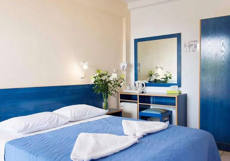 Une chambre lumineuse avec un grand lit et un miroir au-dessus d'une commode.