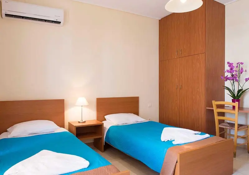 Une chambre lumineuse avec deux lits simples et une décoration sobre.