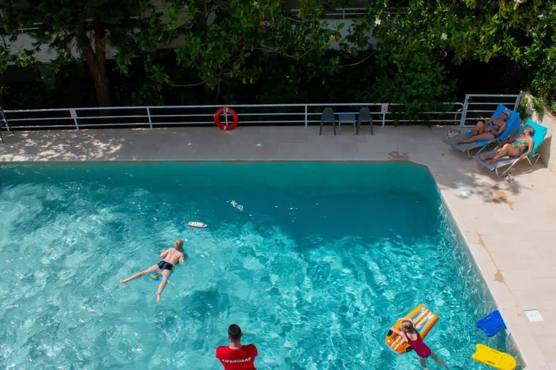 Baigneurs se relaxant au bord d'une piscine ensoleillée.