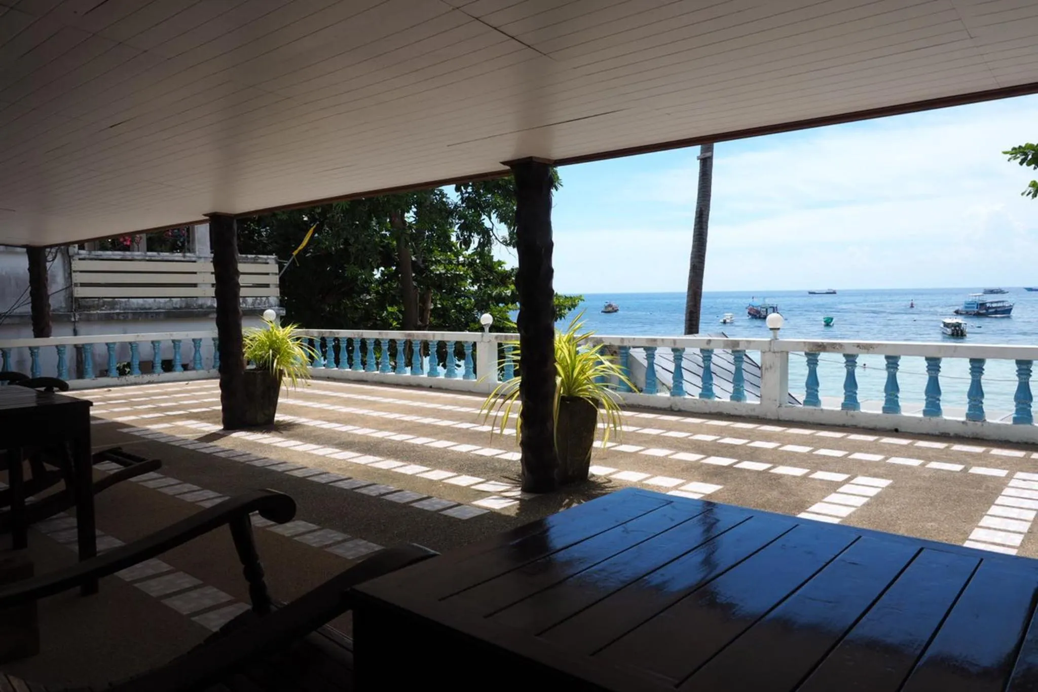 Terrasse ombragée donnant sur la mer et des bateaux.