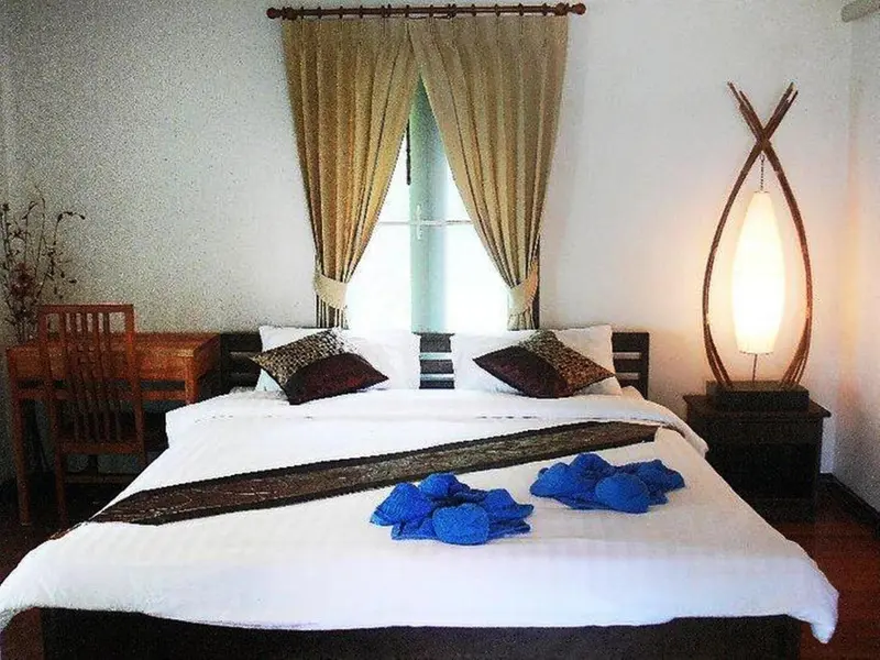 Une chambre lumineuse avec un grand lit recouvert de coussins et de décorations.