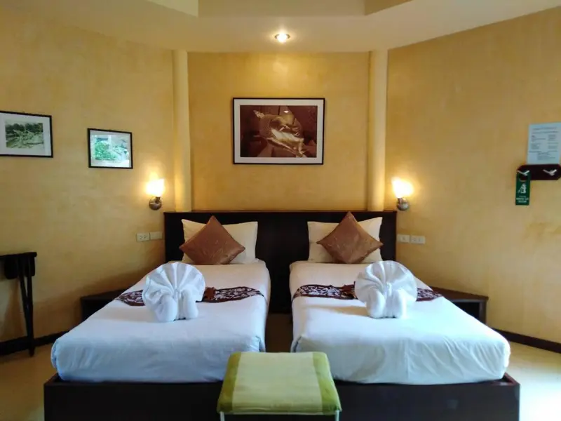 Une chambre avec deux lits simples décorés de serviettes en forme de cygnes.