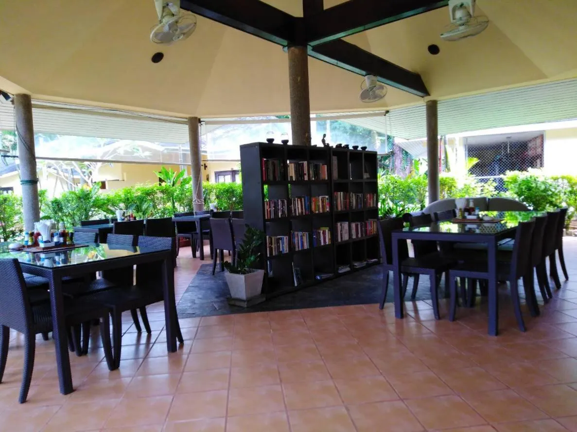 Espace de restauration extérieur avec tables et étagères de livres.