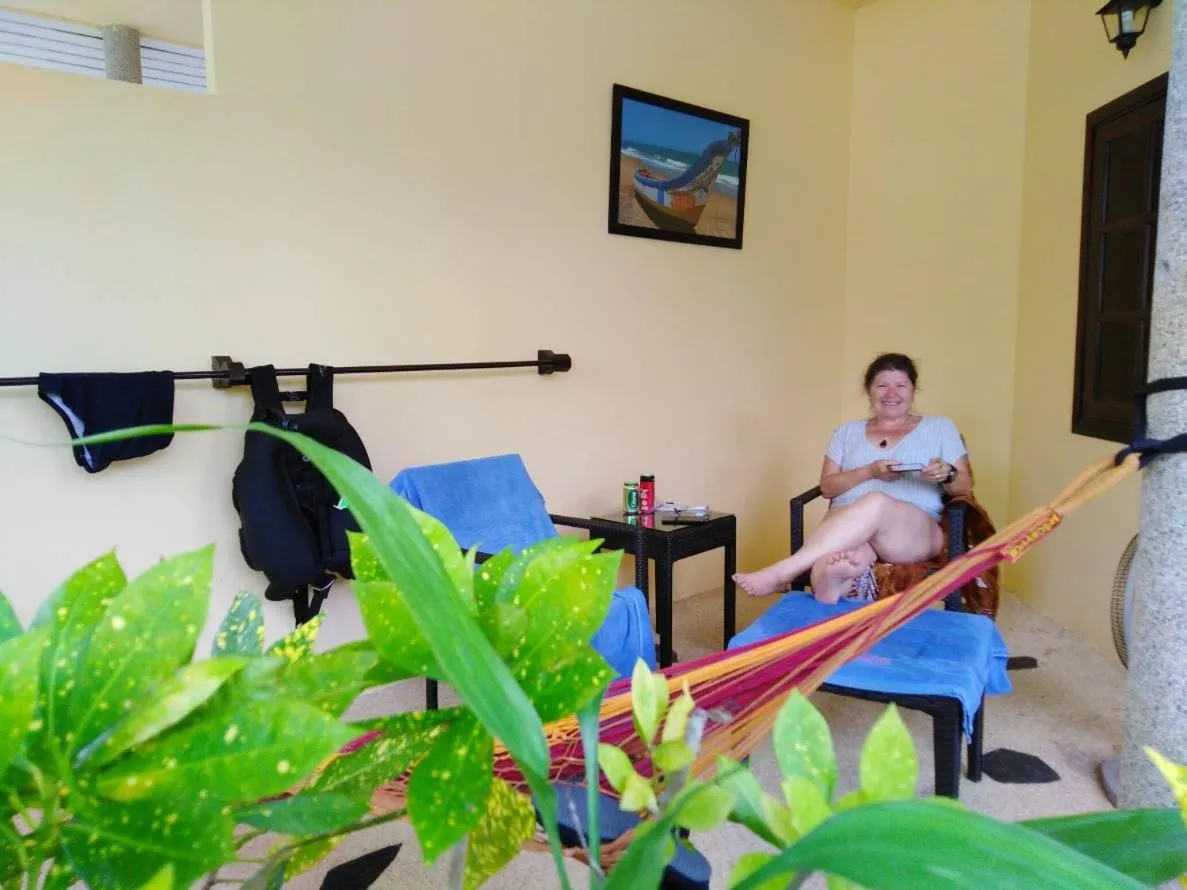 Une femme souriante se détend dans un hamac sur une terrasse.