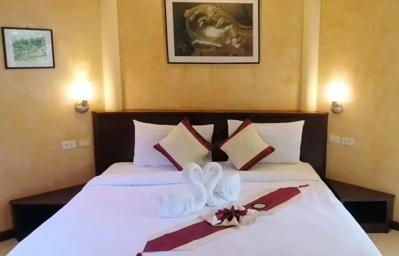 Lit double avec décoration en forme de cygnes sur un drap blanc.