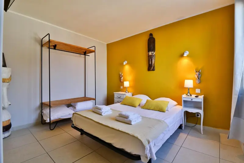 Une chambre lumineuse avec un grand lit et une décoration murale colorée.