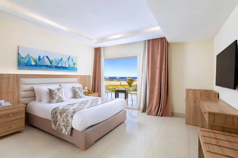 Chambre lumineuse avec un grand lit et vue sur la mer.