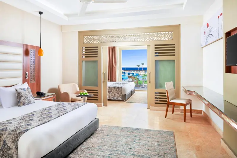 Chambre lumineuse avec un lit double et une vue sur la mer.