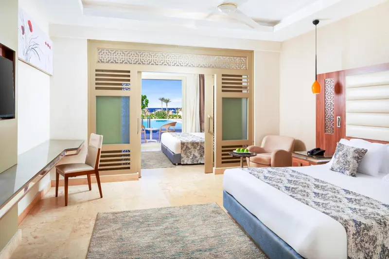 Une chambre lumineuse avec un lit double et un accès à une terrasse avec vue sur la piscine.