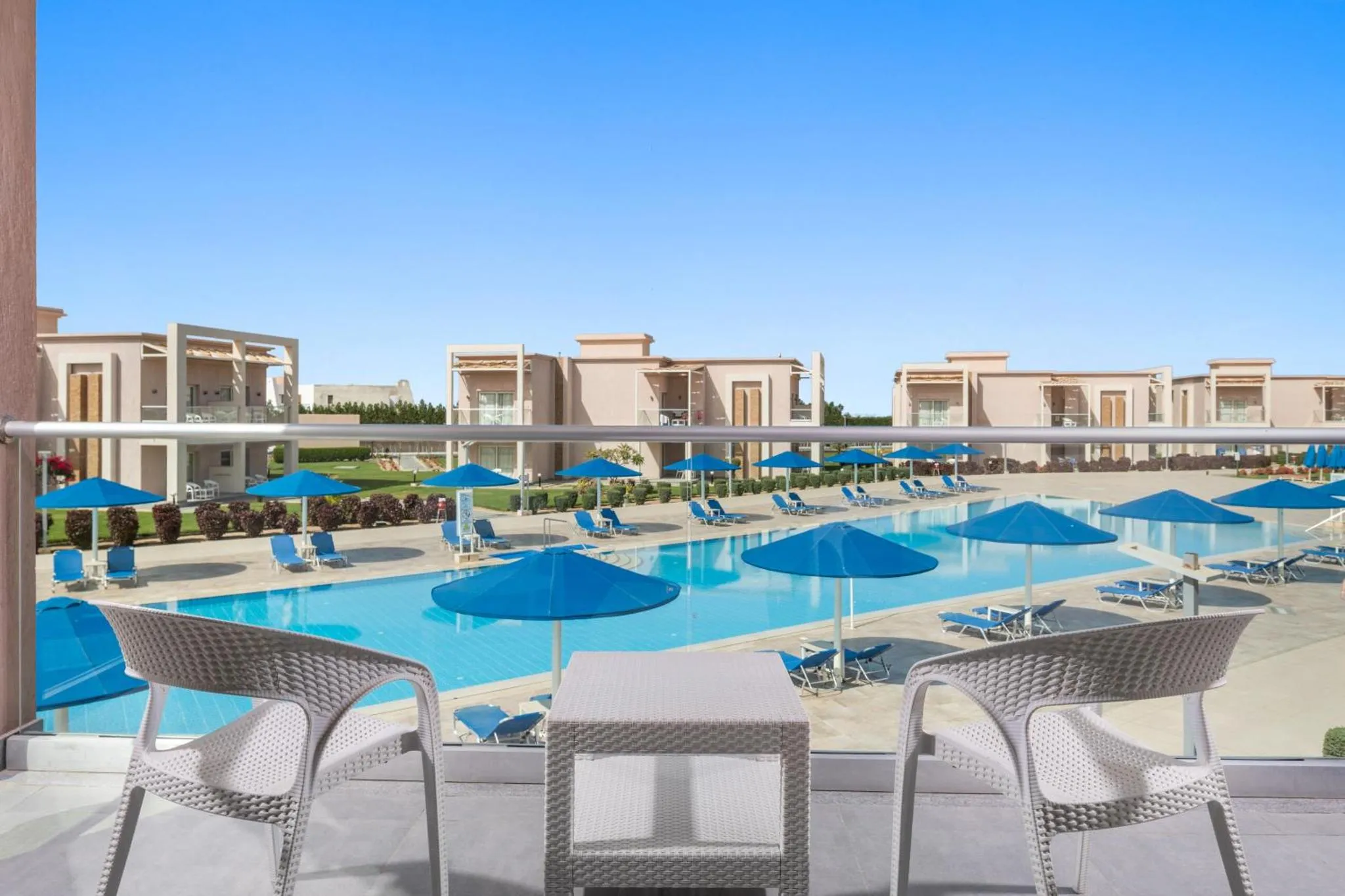 Terrasse avec mobilier en résine donnant sur une piscine et des transats.