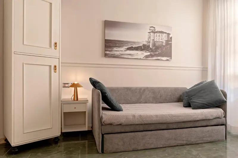 Une chambre lumineuse avec un canapé-lit et une armoire.
