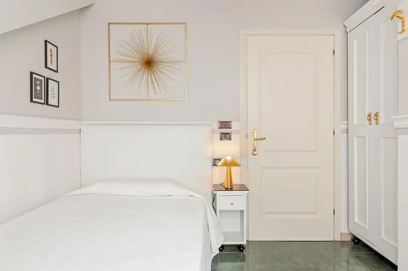 Une chambre lumineuse avec un lit simple et une décoration murale.