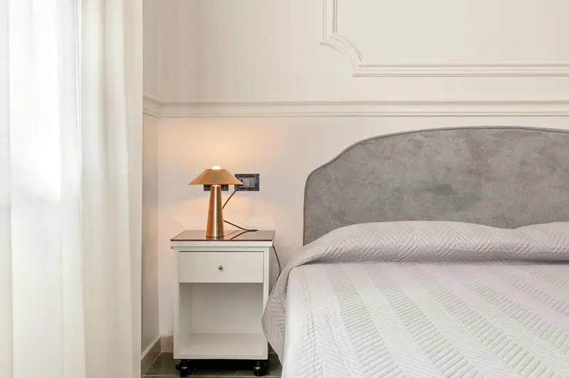 Une chambre lumineuse avec un lit recouvert d'une courtepointe blanche et une table de chevet.