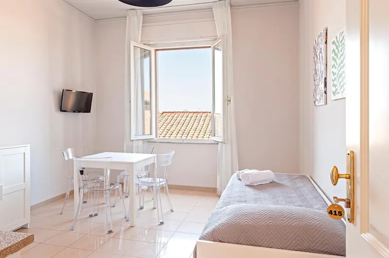 Une pièce lumineuse avec un lit simple, une table et des chaises près d'une fenêtre.