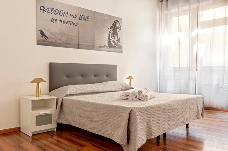 Une chambre lumineuse avec un grand lit et une décoration murale.