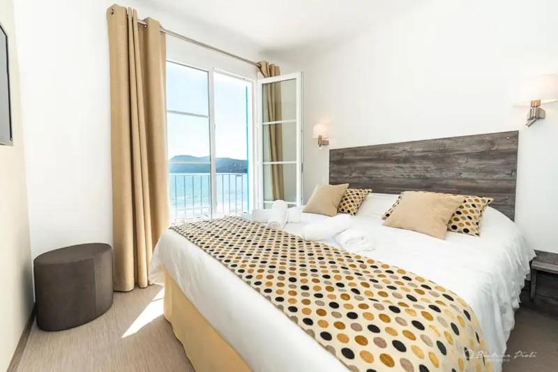 Une chambre lumineuse avec un grand lit et une vue sur la mer.