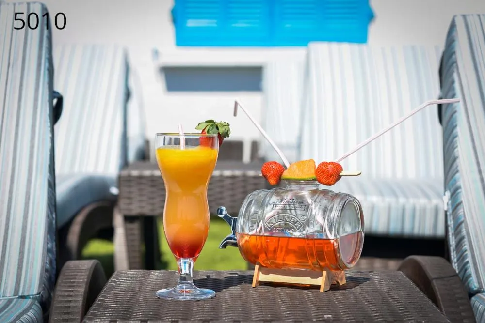 Deux transats avec des boissons colorées sur une terrasse ensoleillée.