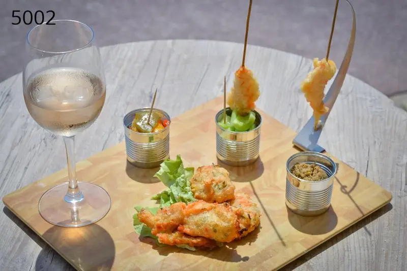 Assortiment de tapas et de boissons sur une table en bois.