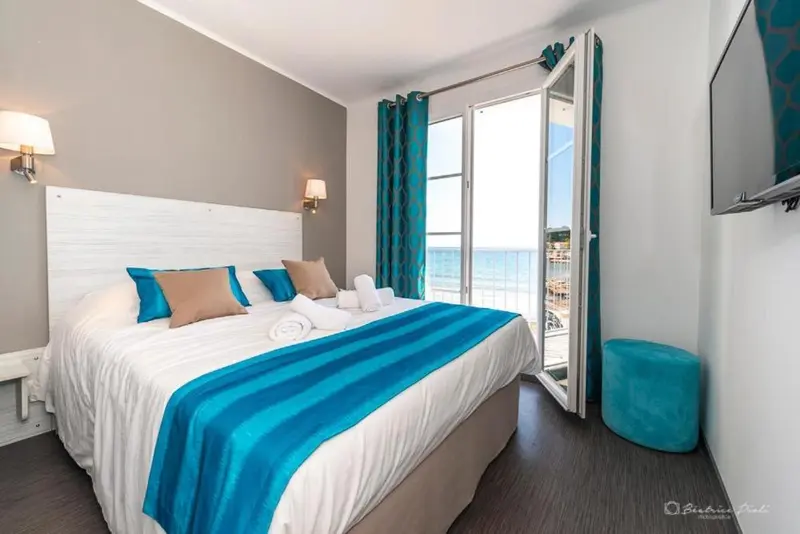Une chambre lumineuse avec un grand lit donnant sur une vue mer.